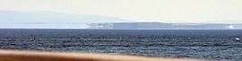 Distant shadowy appearances of land, seen across a wide expanse of sea