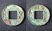 Two circular bronze coins with square holes in the center which have been corroded over time with a green color